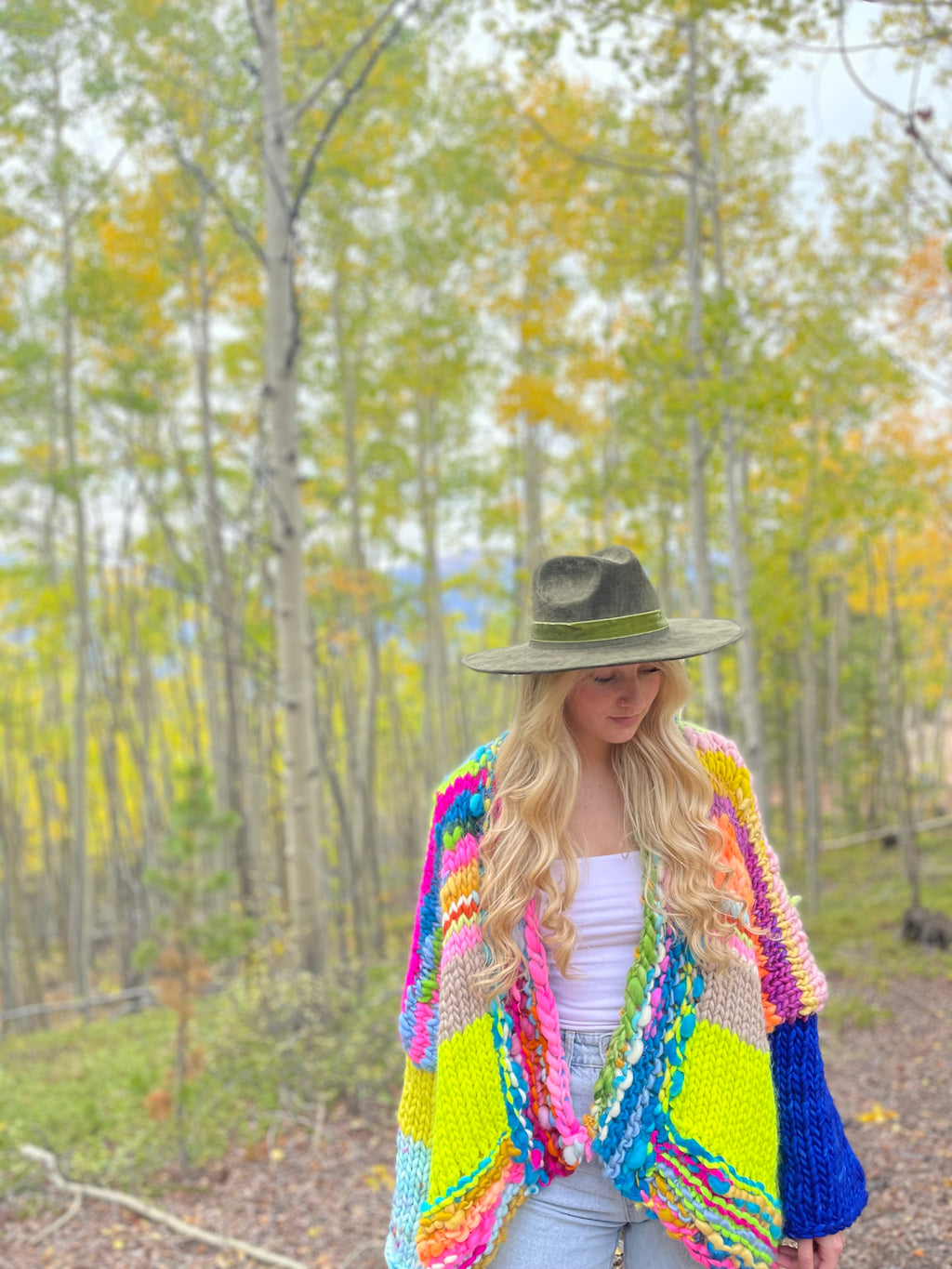 Woman wearing a colorful crochet cardigan in a forest setting