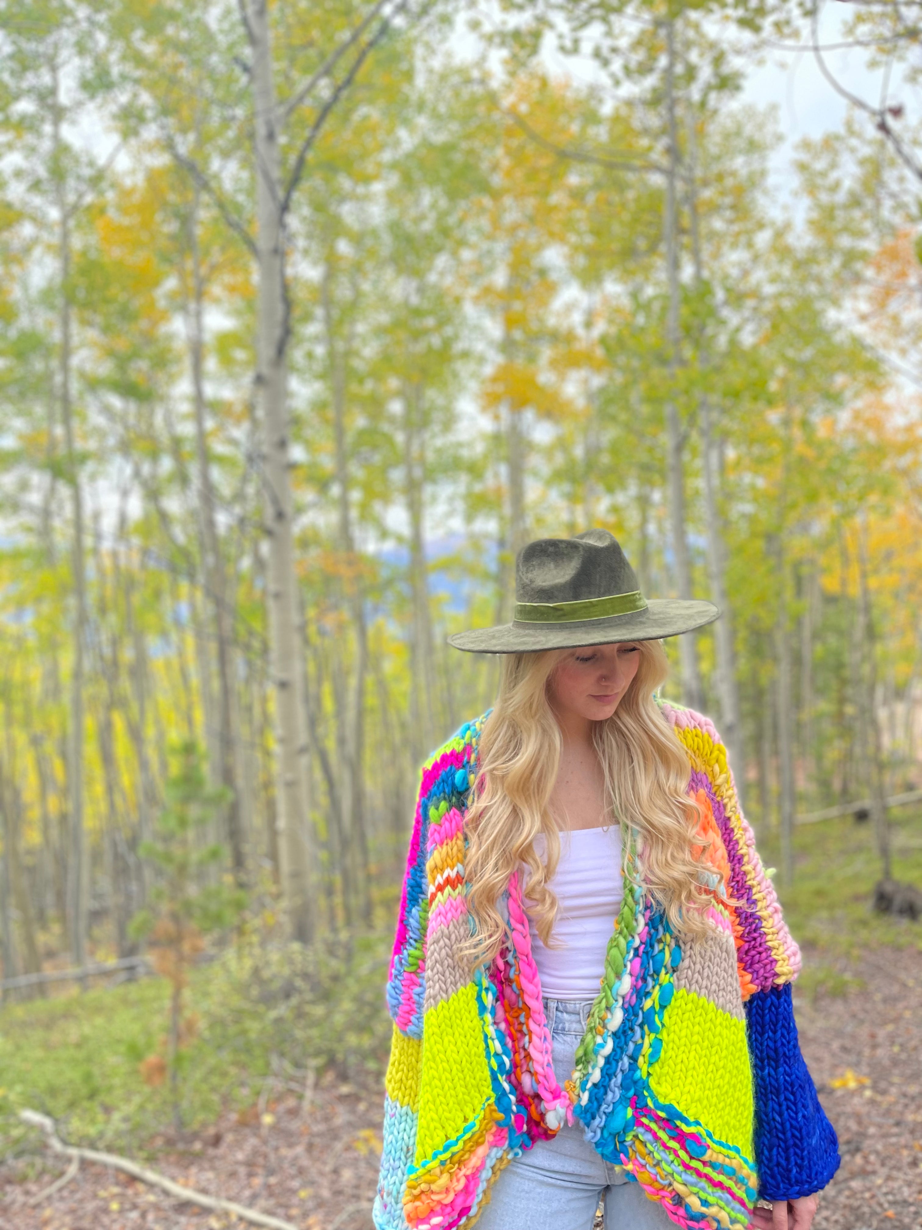 Woman wearing a colorful crochet cardigan in a forest setting